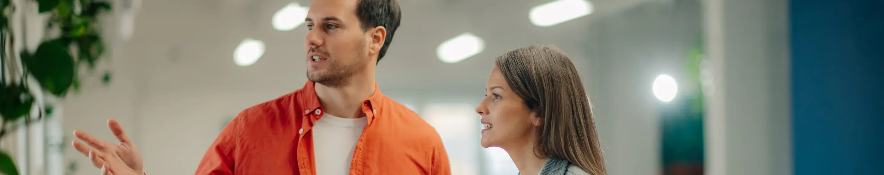 Two colleagues walking and talking in a bright office